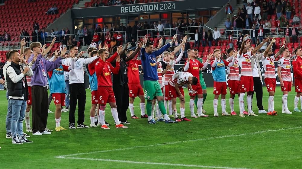 Die Regensburger stehen nach dem Spiel vor ihrer Fankurve. / Foto: Daniel Löb/dpa
