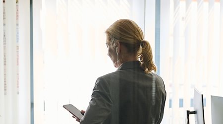 Eine Frau steht in einem Büro. / Foto: Annette Riedl/dpa/Illustration