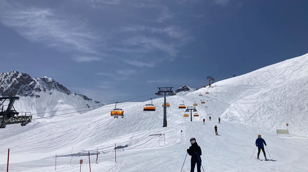 Skifahrer fahren neben einem Lift die Piste hinunter. / Foto: Sabine Dobel/dpa