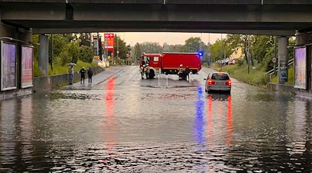 Ein Einsatzfahrzeug der Feuerwehr sichert eine mit Regenwasser vollgelaufene Unterführung ab. / Foto: Ferdinand Merzbach/News5/dpa