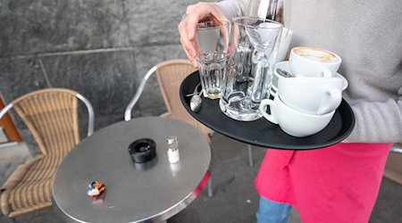 Eine Servicekraft räumt die Tische in einem Café ab. / Foto: Sebastian Gollnow/dpa/Symbolbild