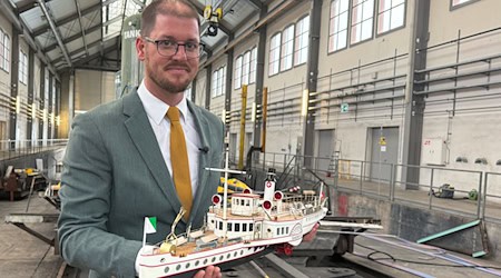 Der Präsident des Schiffsbergevereins, Silvan Paganini, hält ein Modell des 1933 im Bodensee versenkten Dampfschiffs "Säntis" in der Werft der Schweizerischen Bodensee-Schifffahrt in der Hand. / Foto: Aleksandra Bakmaz/dpa