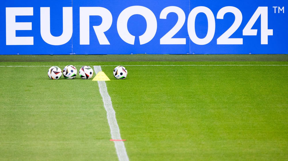 Fußbälle liegen vor einem Schriftzug Euro 2024 bei einer öffentlichen Trainingseinheit. / Foto: Julian Stratenschulte/dpa