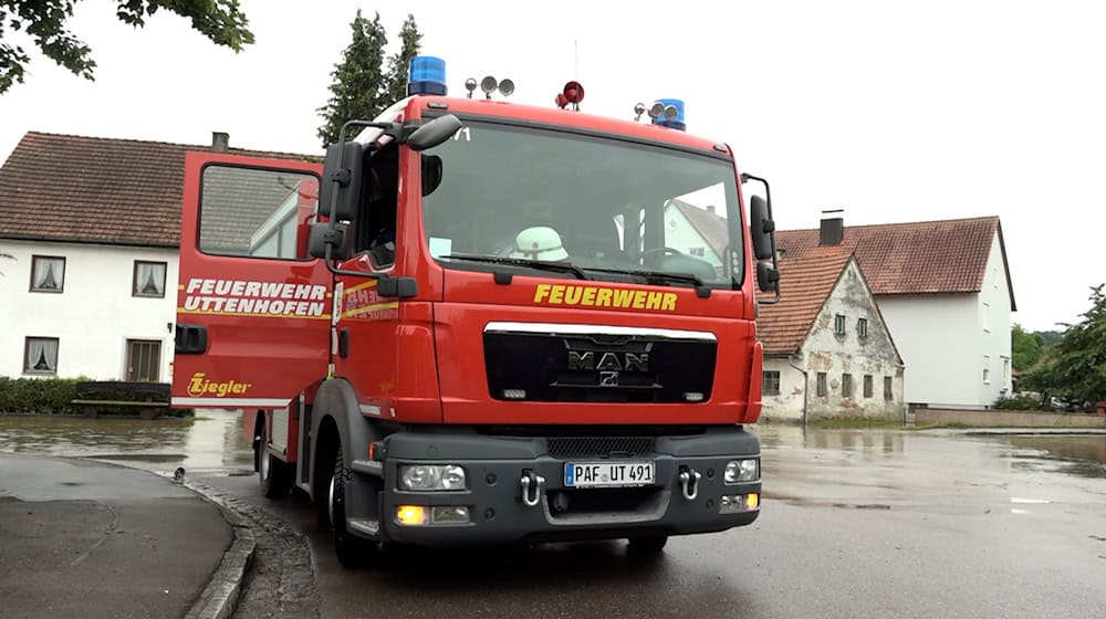 Ein Fahrzeug der Feuerwehr steht neben einer überschwemmten Straße in Pfaffenhofen an der Ilm. / Foto: -/tv7news/dpa