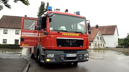 Ein Fahrzeug der Feuerwehr steht neben einer überschwemmten Straße in Pfaffenhofen an der Ilm. / Foto: -/tv7news/dpa