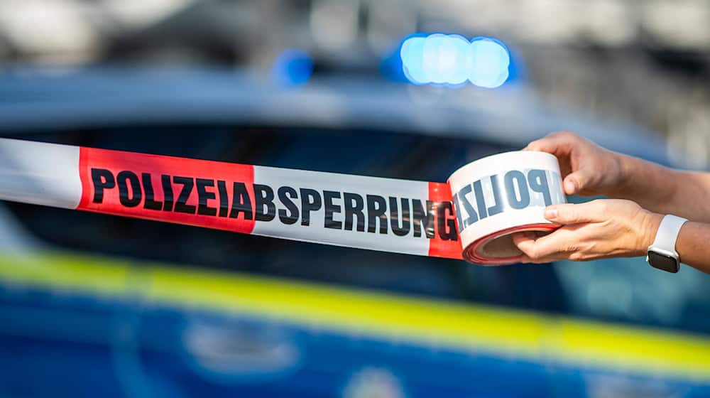 Ein Absperrband wird vor einem Polizeiwagen ausgerollt. / Foto: David Inderlied/dpa/Illustration