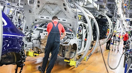 Ein Mitarbeiter arbeitet in einer Autofabrik an einer Karosserie. / Foto: Jan Woitas/dpa