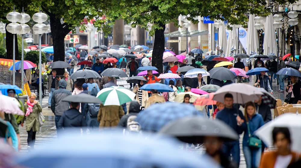 Passanten mit Regenschirmen laufen im Regen durch die Fußgängerzone Neuhauser Straße und Kaufingerstraße nahe dem Stachus in München. / Foto: Matthias Balk/dpa
