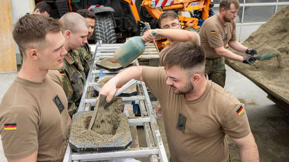 In einem Betonwerk füllen Soldaten der Bundeswehr Sandsäcke ab. / Foto: Stefan Puchner/dpa