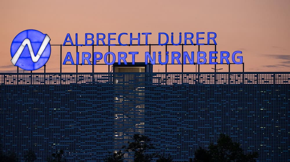 Der Schriftzug «Albrecht Dürer Airport Nürnberg» leuchtet auf dem Dach eines Parkhauses am Flughafen am Abend. / Foto: Daniel Karmann/dpa