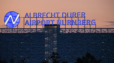 Der Schriftzug «Albrecht Dürer Airport Nürnberg» leuchtet auf dem Dach eines Parkhauses am Flughafen am Abend. / Foto: Daniel Karmann/dpa