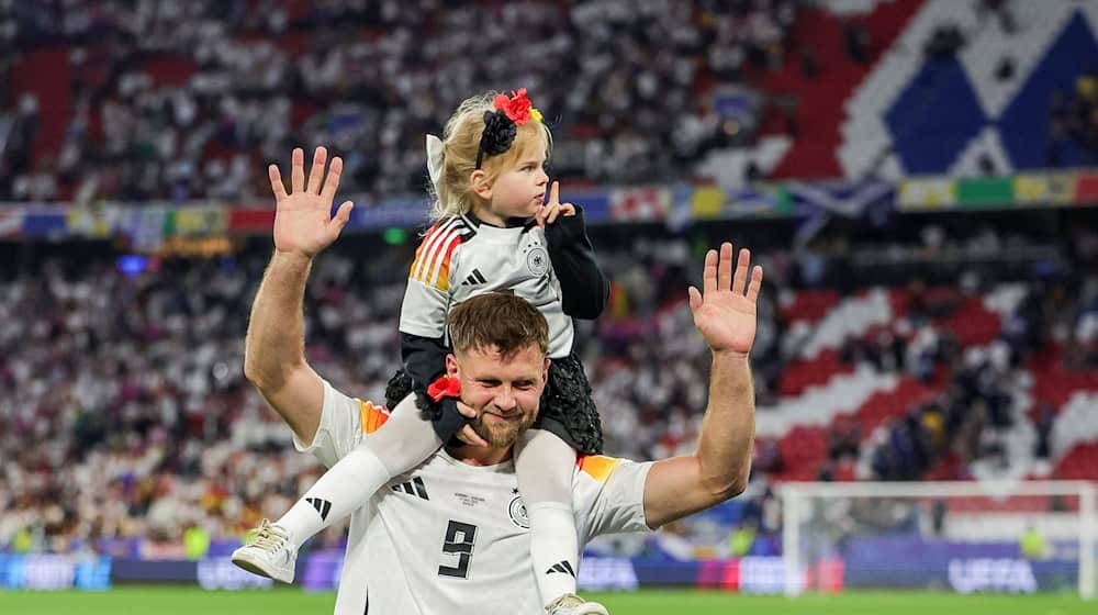 Deutschlands Spieler Niclas Füllkrug trägt nach dem Sieg seine Tochter Emilia durch das Stadion. / Foto: Christian Charisius/dpa