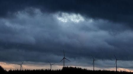 Windräder stehen bei Aitrang im Allgäu unter dichten Regenwolken hinter einem Wald. / Foto: Karl-Josef Hildenbrand/dpa/Archivbild
