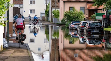 Radler fahren durch eine überflutete Straße. / Foto: Armin Weigel/dpa