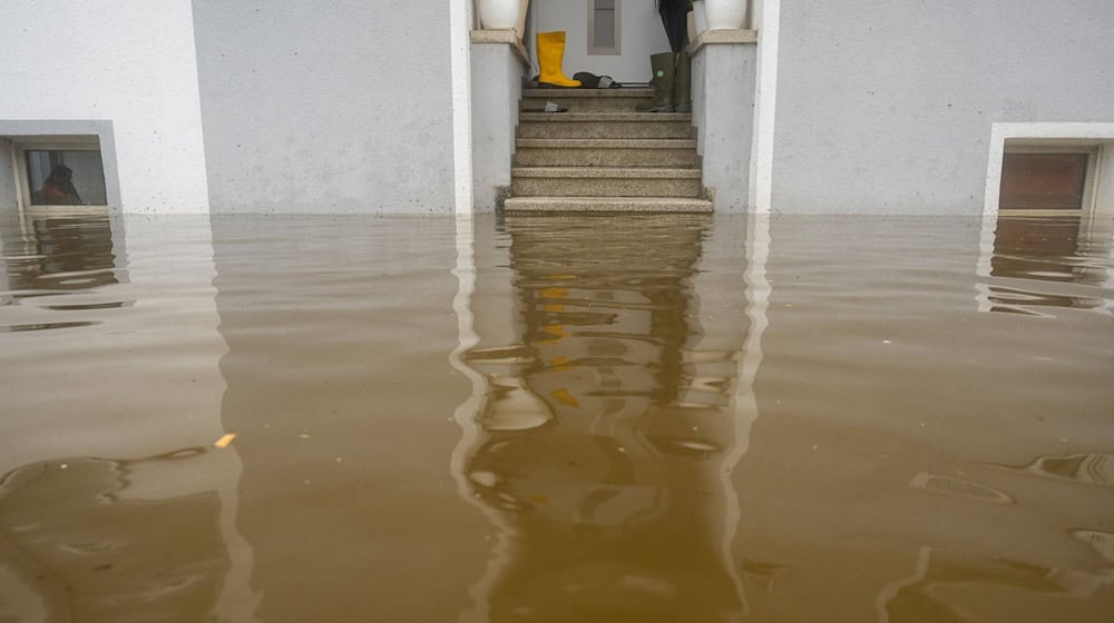 Im Treppenaufgang eines Hauses, dessen Untergeschoss voll Wasser ist, stehen Gummistiefel. / Foto: Stefan Puchner/dpa