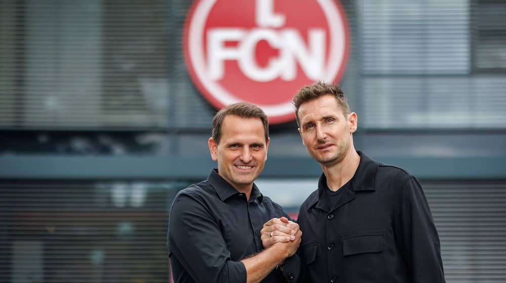 Der neue FCN-Trainer Miroslav Klose (r) steht mit dem FCN-Sportvorstand Joti Chatzialexiou vor dem Vereins-Logo. Klose übernimmt das Traineramt beim 1. FC Nürnberg. Der ehemalige deutsche Nationalspieler unterschreibt beim Zweitligisten einen Zweijahresvertrag. / Foto: Daniel Karmann/dpa