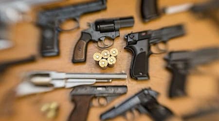 Pistolen und Revolver und Munition liegen auf einem Tisch in einer gesicherten Asservatenkammer. / Foto: Friso Gentsch/dpa/Archivbild