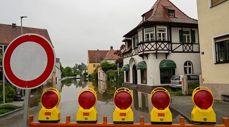 Vor einer überfluteten Straße steht eine Absperrung. / Foto: Stefan Puchner/dpa