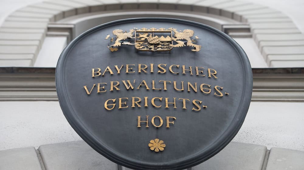 Ein Metallschild mit der Aufschrift «Bayerischer Verwaltungsgerichtshof» hängt an der Fassade des bayerischen Verwaltungsgerichtshofs. / Foto: Peter Kneffel/dpa/Archivbild