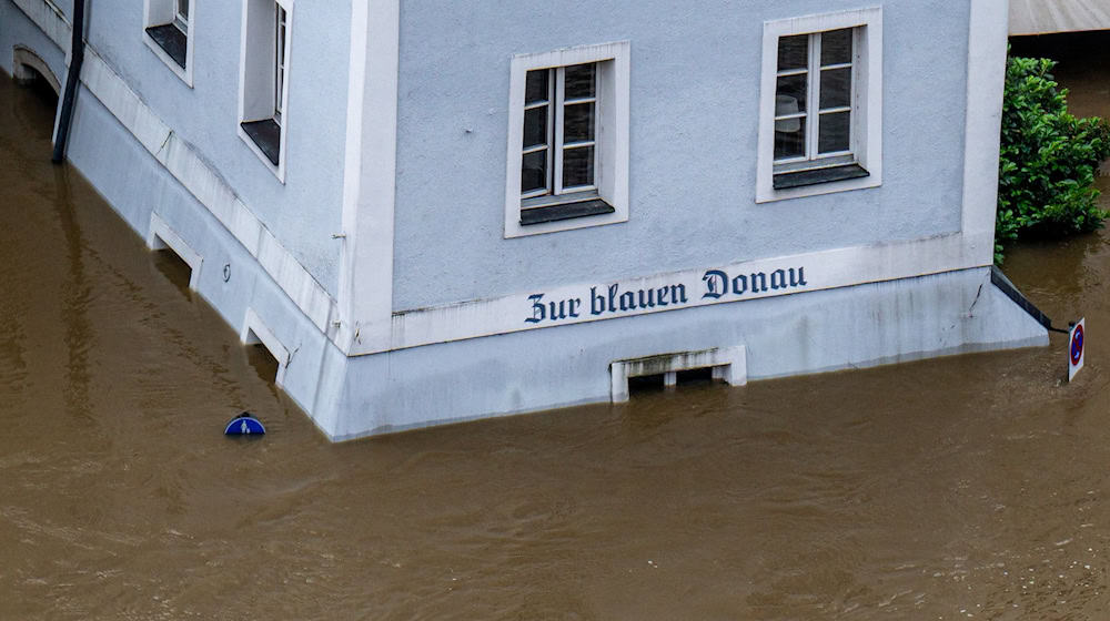 Ein Haus mit dem Schriftzug "Zur blauen Donau" steht im Hochwasser der Donau. / Foto: Armin Weigel/dpa