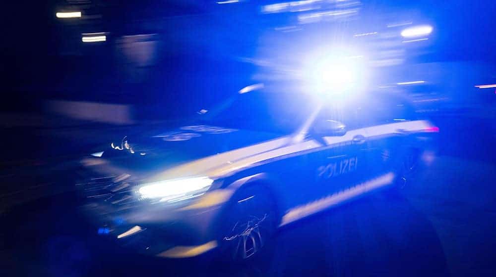 Ein Polizeifahrzeug fährt mit Blaulicht an einem Gebäude vorbei. / Foto: Marijan Murat/dpa
