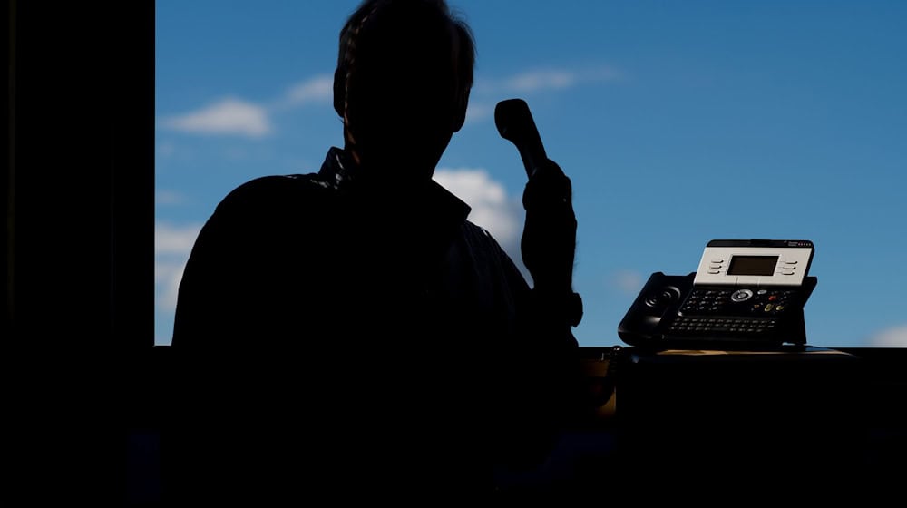 Ein Mann mit Telefonhörer in der Hand. / Foto: Julian Stratenschulte/dpa/Illustration