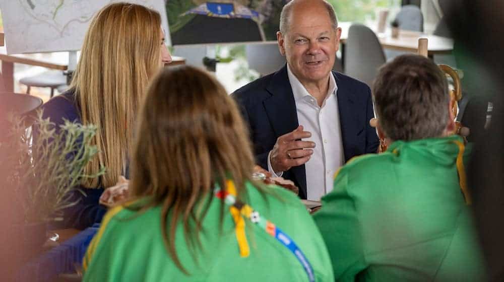 Bundeskanzler Olaf Scholz (SPD) unterhält sich im Olympia Stadion in München mit Volunteers. / Foto: Peter Kneffel/dpa