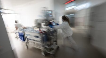 Eine Pflegerin fährt eine Intensivpatientin in einem Krankenbett durch einen Gang einer Klinik. / Foto: Marijan Murat/dpa