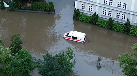 Ein Krankenwagen fährt über eine überschwemmte Straße in Schrobenhausen im Landkreis Neuburg-Schrobenhausen. / Foto: -/tv7news/dpa