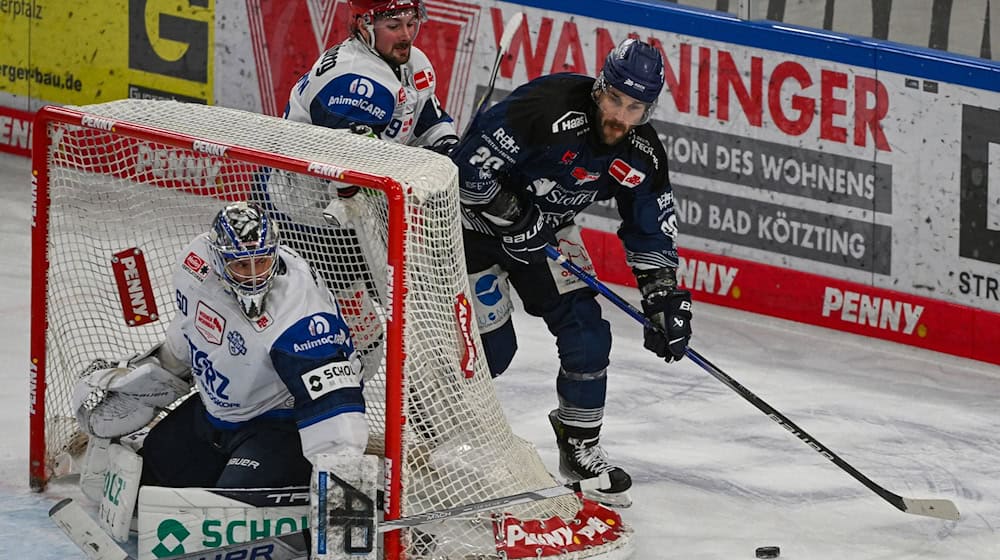 Justin Scott (r) von den Straubing Tigers versucht, den Puck ins Tor von Joacim Eriksson von den Schwenninger Wild Wings zu bekommen. Scott verlängert seinen Vertrag in Straubing. / Foto: Armin Weigel/dpa