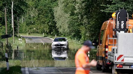 Fahrzeuge stehen vor einer überfluteten Straße im Landkreis Rosenheim. In Bayern herrscht nach heftigen Regenfällen vielerorts weiter Land unter. Zehntausende Helfer sind seit Tagen im Einsatz. / Foto: Uwe Lein/dpa