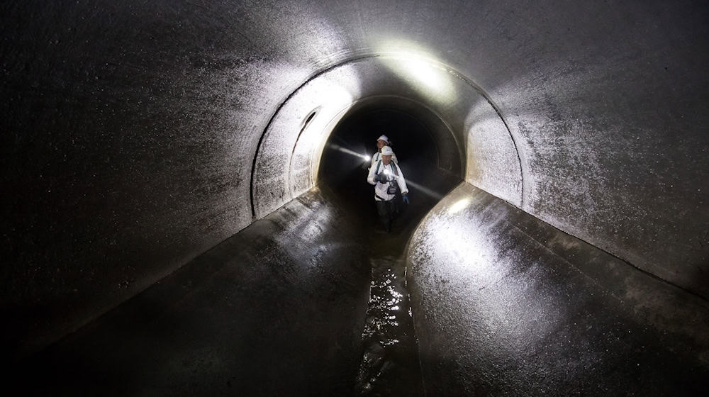 Kanalarbeiter begehen während eines Kontrollgangs die unterirdische Kanalisation. / Foto: Daniel Karmann/dpa