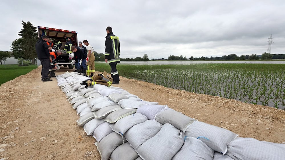 Feuerwehrleute und freiwillige Helfer befestigen im Ortsteil Auchsesheim nach einem Dammbruch einen zweiten Damm mit Sandsäcken um das Hochwasser der Zusam zu stoppen. / Foto: Karl-Josef Hildenbrand/dpa