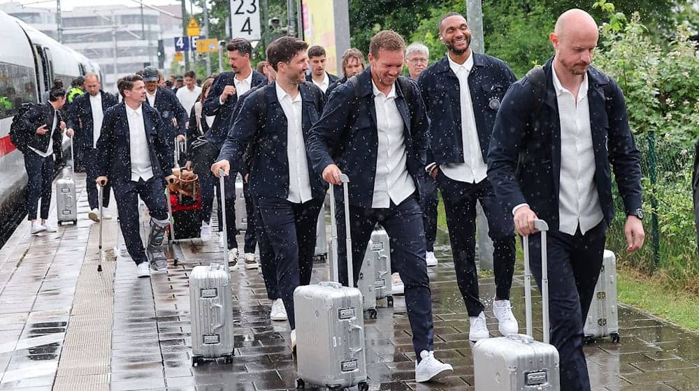 Bundestrainer Julian Nagelsmann (3.v.r) und Spieler Jonathan Tah (2.v.r) lächeln bei der Ankunft am Bahnhof. / Foto: Daniel Löb/dpa