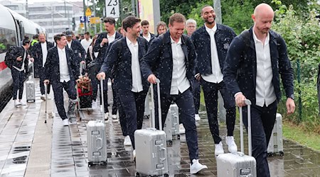 Bundestrainer Julian Nagelsmann (3.v.r) und Spieler Jonathan Tah (2.v.r) lächeln bei der Ankunft am Bahnhof. / Foto: Daniel Löb/dpa