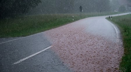 Das Regenwasser spült Erde über eine Straße. Regenwolken ziehen über Südthüringen und es regnet stark. / Foto: Daniel Vogl/dpa