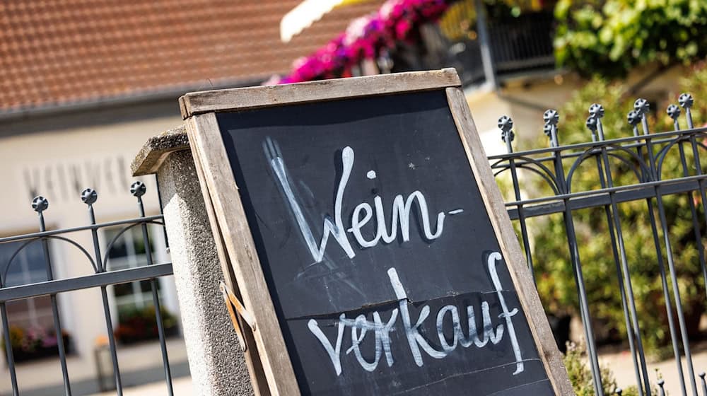 Ein Schild mit der Aufschrift «Weinverkauf» lehnt an einem Zaun. / Foto: Matthias Balk/dpa/Symbolbild