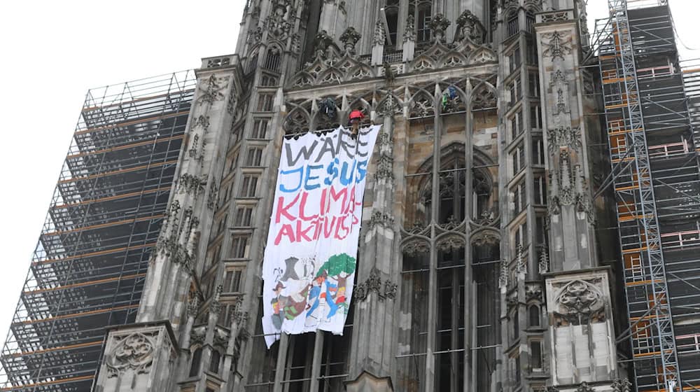 Klimaaktivisten haben am Ulmer Münster mit dem höchsten Kirchturm der Welt ein Protestbannner entrollt. / Foto: Ralf Zwiebler/dpa