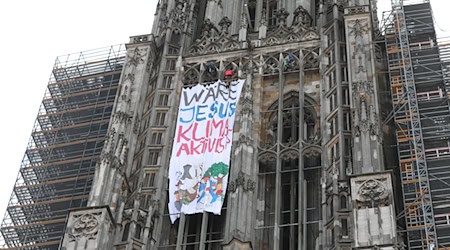 Klimaaktivisten haben am Ulmer Münster mit dem höchsten Kirchturm der Welt ein Protestbannner entrollt. / Foto: Ralf Zwiebler/dpa