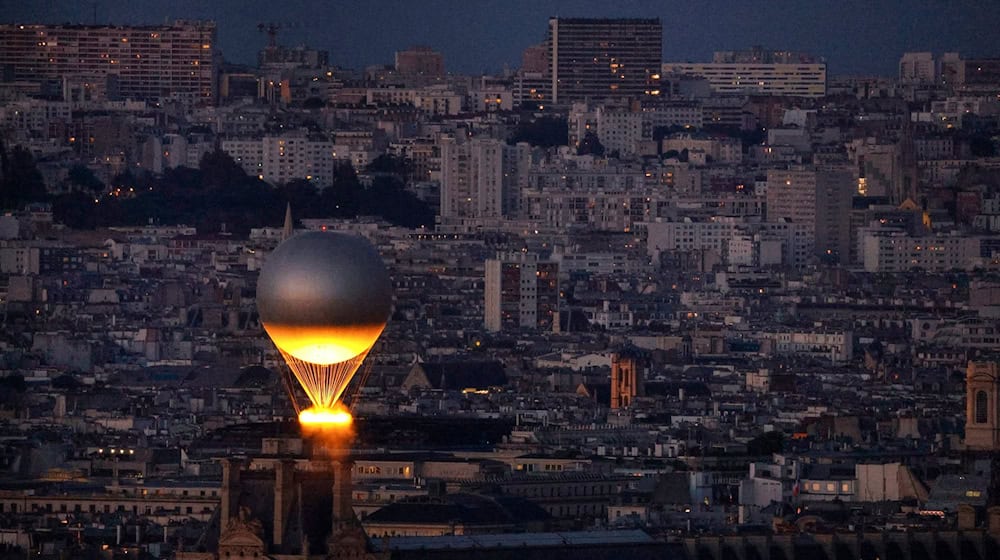 Der Kessel mit dem Olympischen Feuer fliegt an einem Ballon befestigt über Paris. Der Heliumballon stammt von einem darauf spezialisierten Unternehmen aus Augsburg. (Archivbild) / Foto: Geoffroy Van Der Hasselt/Pool AFP/AP/dpa