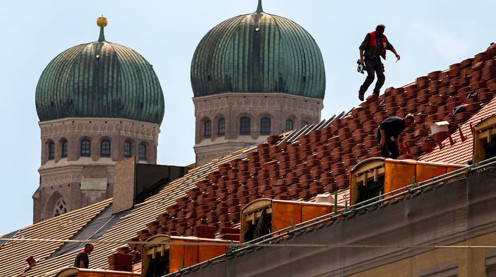 Dachdecker auf einem Hausdach vor der Kulisse der Münchner Frauenkirche / Foto: Peter Kneffel/dpa