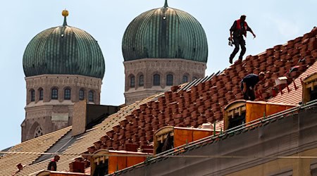 Dachdecker auf einem Hausdach vor der Kulisse der Münchner Frauenkirche / Foto: Peter Kneffel/dpa