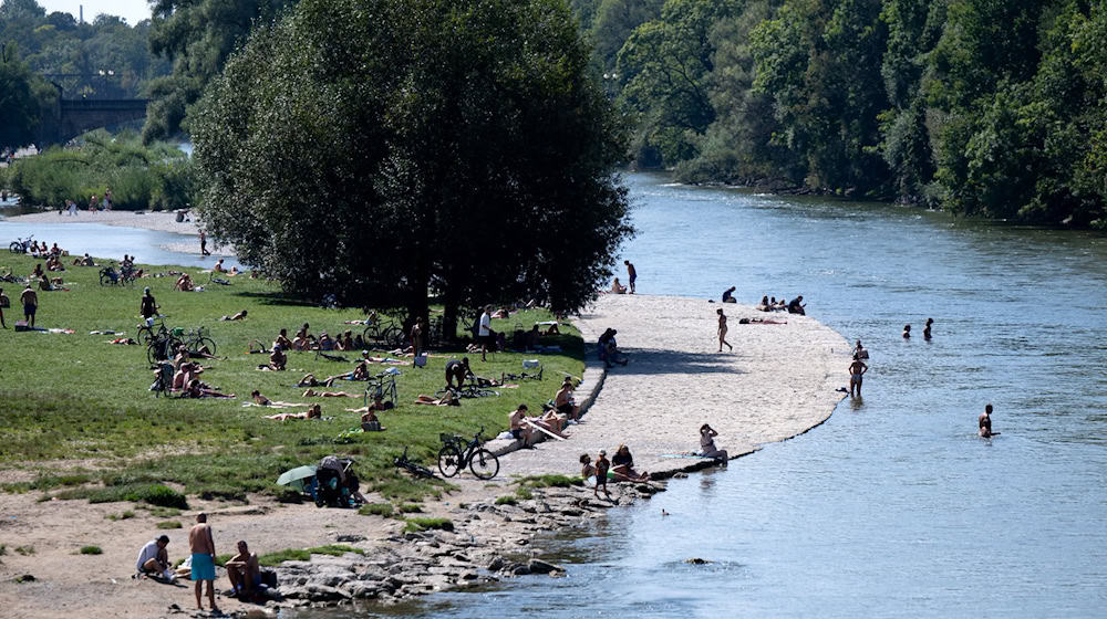 Zahlreiche Menschen genießen das sonnige Wetter in der Münchner Innenstadt am Ufer der Isar. (Archivbild) / Foto: Sven Hoppe/dpa