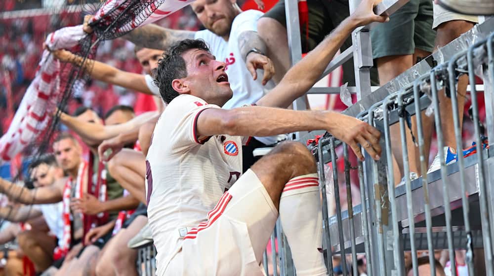 Thomas Müller steigt nach dem Bayern-Sieg auf den Zaun zu den Fans. / Foto: Sven Hoppe/dpa