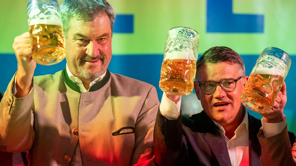 Markus Söder (l, CSU), Ministerpräsident von Bayern, und Boris Rhein (r, CDU), Ministerpräsident von Hessen, stoßen beim Politischen Frühschoppen Gillamoos gemeinsam auf der Bühne mit einer Maß Bier an.  / Foto: Peter Kneffel/dpa