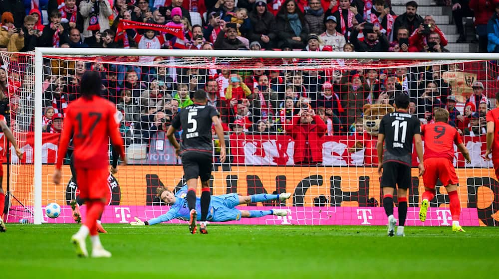 Harry Kane (r) schießt den Elfmeter in die Ecke, die ihm Union-Torwart Frederik Rönnow anzeigte. / Foto: Tom Weller/dpa