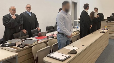 Von links nach rechts: Die Anwälte Klaus Wittmann und Thilo Bals, ein Angeklagter, Anwalt Johannes Makepeace, eine Angeklagte und Anwalt Alexander Stevens stehen zu Beginn der Fortsetzung ihres Prozesses im Gerichtsaal. Im Mordprozess um den Tod einer Doppelgängerin der angeklagten Frau stehen nun die Plädoyers der Verteidiger an. (Archivfoto) / Foto: Sabine Dobel/dpa