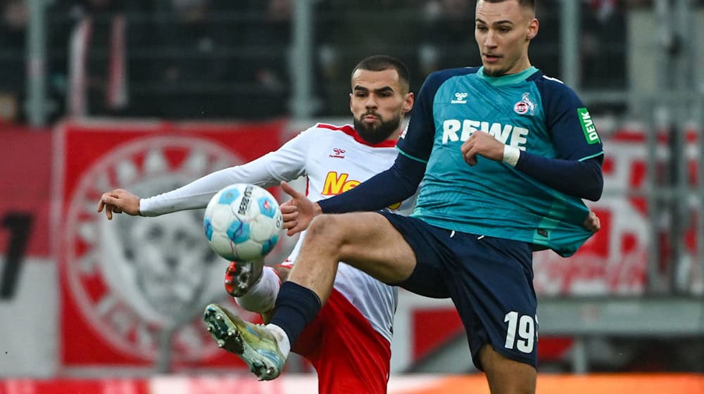 Der Kölner Tim Lemperle (rechts) und Robin Ziegele von Regensburg kämpfen um den Ball. / Foto: Armin Weigel/dpa
