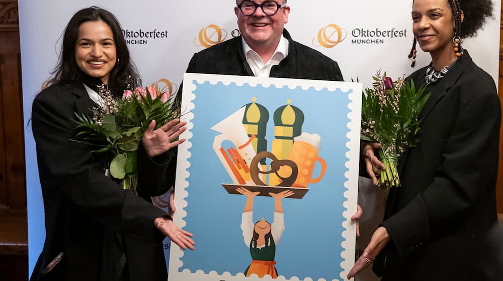 Wiesnchef Clemens Baumgärtner (M.) präsentiert mit den Künstlerinnen Amiera Harithas (l.) und Dinah-Charles Francis das offizielle Motiv zum Oktoberfest 2025. / Foto: Lukas Barth/dpa