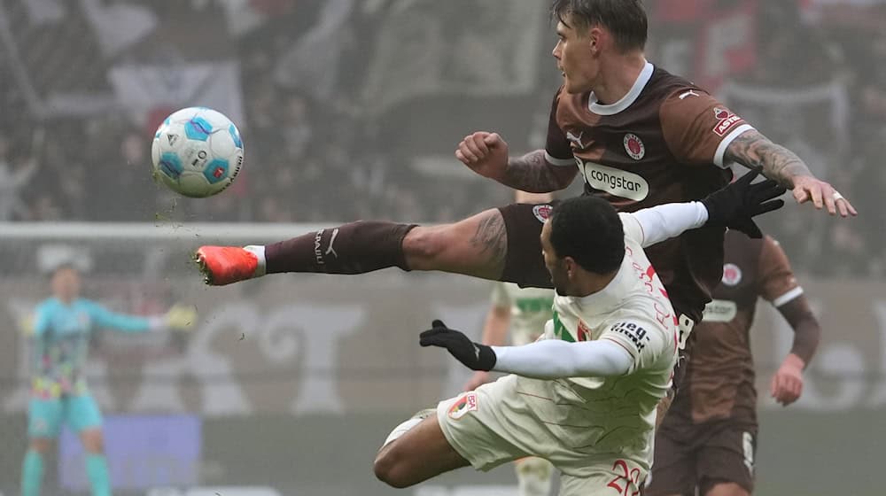  St. Paulis Eric Smith (r) und Augsburgs Alexis Claude-Maurice kämpfen um den Ball. / Foto: Marcus Brandt/dpa